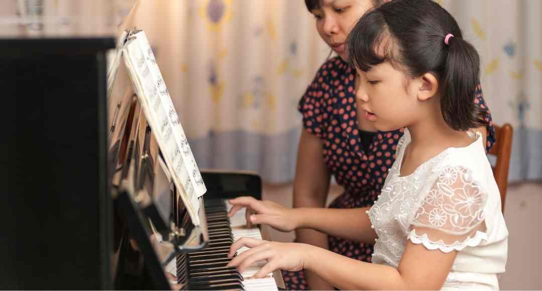 child playing piano with an instructor by the side